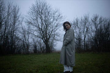 gloomy woman in coat walks alone in foggy field, existential crisis