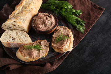 Plate with toasts, bowl of tasty pate, parsley and dill on black grunge background