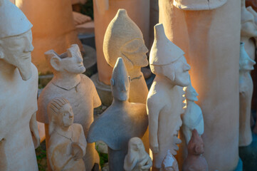 Artisans create unique clay sculptures at a vibrant outdoor market during sunset
