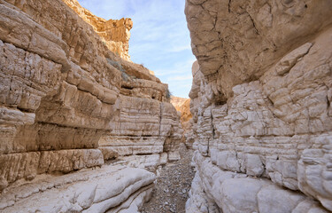 View inside a deep dry canyon in a remote desert region. High walls of a narrow canyon in the Negev Desert. Hiking trail in a heart of the desert.