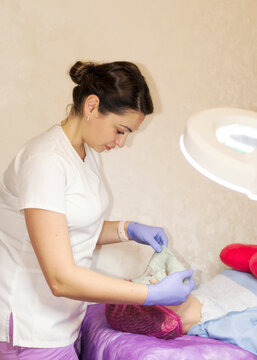 A female cosmetologist doctor makes a facial mask for a client
