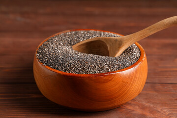 Bowl with chia seeds and spoon on wooden background
