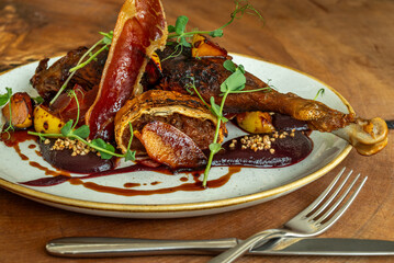 Gourmet duck leg with crispy ham and roasted vegetables
