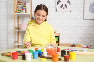Cute girl painting on table at home