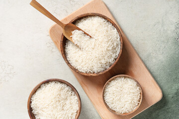 Wooden bowls with raw rice and scoop on grunge background