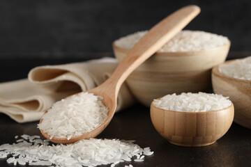 Wooden bowls with raw rice and spoon on black grunge background