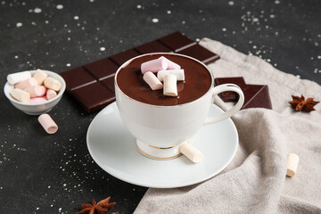 Cup of hot chocolate with marshmallows and star anise on black grunge background