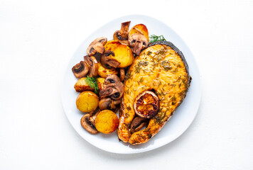 Baked salmon steak with lemon and dill, fried baby potatoes with mushrooms and cream sauce. White background, top view