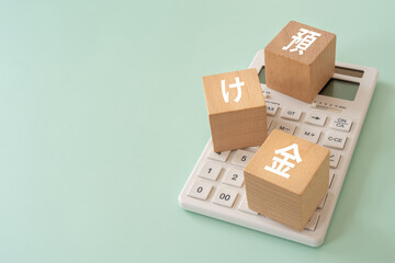 預け金と書かれたブロックと電卓