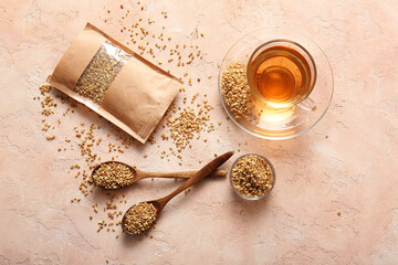 Glass cup of hot buckwheat tea with pack, wooden spoons on beige grunge background