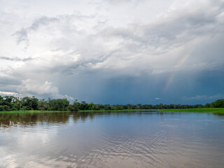 Amazon river landscape with rainbow and rainforest.