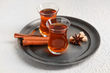 Tray with glasses of Turkish tea, sugar cubes, cinnamon sticks and star anise on white background