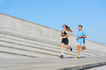 Obraz premium Couple enjoys a morning jog on a sunny day at an urban park with modern architecture