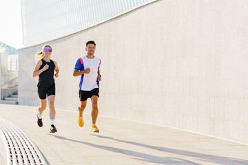 Obraz premium Joggers enjoy a sunny morning run along a modern urban path near contemporary architecture