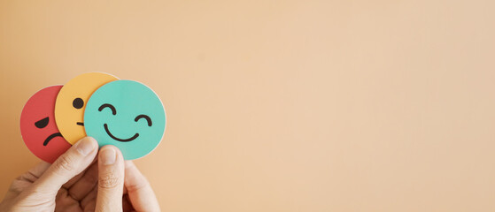 Hands holding sad face hiding behind happy face, psychology and mental health, emotional...
