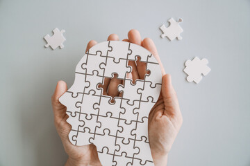 Hands holding brain with puzzle paper cutout, autism, dementia, Epilepsy and Alzheimer awareness, seizure disorder, world mental health day concept
