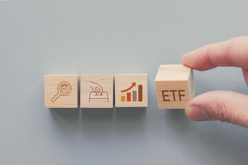 Hands holding wooden blocks with ETF and icons, exchange traded funds, retirement plan concept
