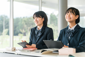 タブレット端末を使いながら勉強する中学生・高校生の女子生徒
