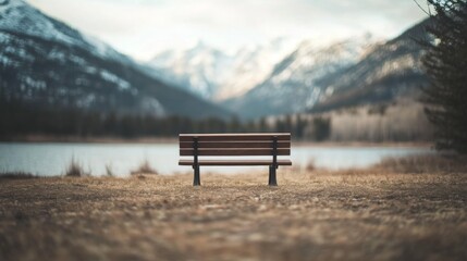 Empty park bench overlooking serene lake and snow-capped mountains.
