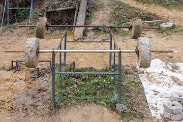 Two barbells with concrete pancakes on a homemade rack of an outdoor sports ground for the poor.