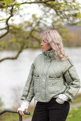 Woman enjoys a peaceful moment by the river while wearing a cozy quilted jacket on a cool day