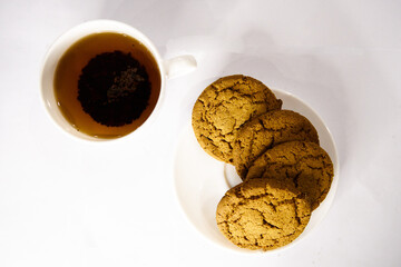 Oatmeal cookies on a white plate and a cup of black tea