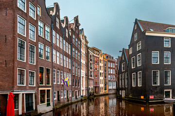 Colorful Dutch canal houses reflecting in the water of a narrow canal in Amsterdam. The unique architecture and bright facades create a vibrant and charming urban scene