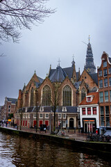 A striking view of the historic Oude Kerk (Old Church) in Amsterdam, Netherlands, with its Gothic architecture and towering spire standing prominently.