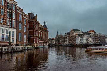 Naklejka premium A stunning view of Amsterdam's historic canal lined with elegant brick buildings, showcasing intricate Dutch architecture.