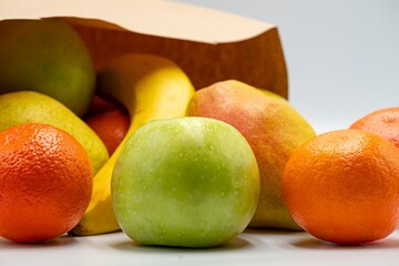 Fresh ripe fruits in paper bags on white background.