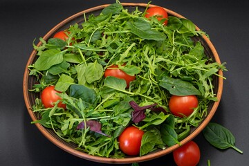 Healthy eating. Fresh salad with spinach, tomatoes and arugula in a plate on a gray background.