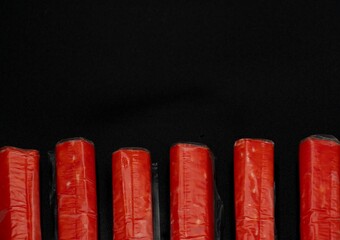 Crab sticks on a black background with space for text laid out in a row © Olha