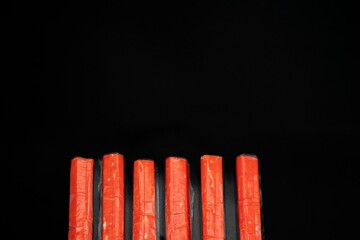 Crab sticks on a black background with space for text laid out in a row © Olha
