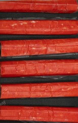 Crab sticks on a black background with space for text laid out in a row © Olha