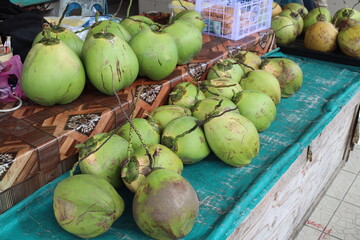 rows of fresh coconuts displayed for sale at a stall in an open air hawker market