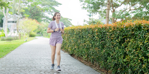 Energetic young woman jogging with a towel in a peaceful park, embracing outdoor fitness