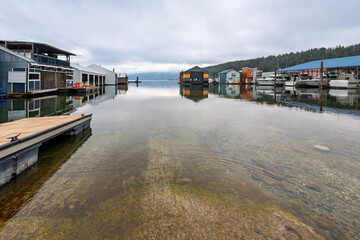 Winter view of the Bayview marina with docks, boat houses and float homes in the glassy waters of Lake Pend Oreille in Bayview, Idaho, in the North Idaho panhandle region.
