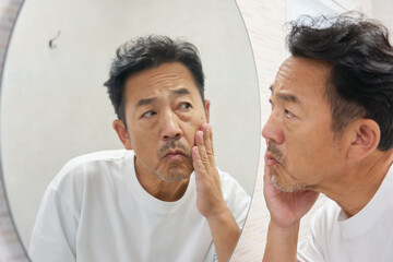 鏡を見て悩む50代男性
