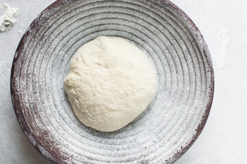 Overhead view of bread dough rising in banneton basket , top view of proofing dough in a wood proofing basket, process of making artisan bread