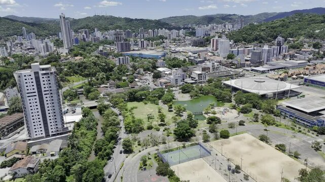 Drone orbits high over Ramiro Ruediger Park with the Vila Germ&acirc;nica in the distance on a sunny afternoon in Blumenau, Santa Catarina, Brazil