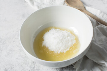 Overhead view of oil and sugar in a white bowl, the process of making a cake and cookies, mixing oil and sugar to make a cake and cookies