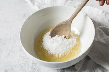 Creaming oil and sugar with a wooden spoon, the process of making a cake and cookies, mixing butter and sugar to make a cake and cookies