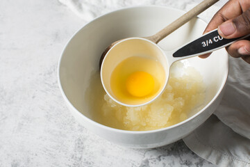 Overhead view of raw egg, whole raw egg in a white measuring cup