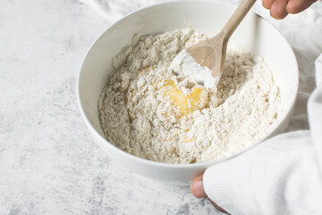 mixing flour into vanilla cookie dough in a white mixing bowl, plain vanilla cookie dough about to be baked, process of making vanilla cookie dough