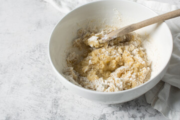 mixing flour into vanilla cookie dough in a white mixing bowl, plain vanilla cookie dough about to be baked, process of making vanilla cookie dough