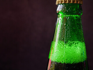 Close up of cold  beer bottles green and beer bubbles in bottles with water drops on black background.