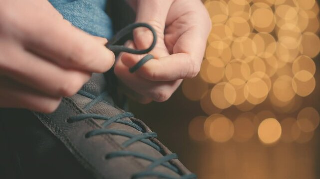 Tying Shoe Laces on Winter Nubuck Boot Close Up, Leather Footwear with Golden Bokeh Background, Man Lacing Up Casual Boot