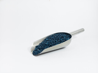 Dark blue masterbatch, polymer granules carrying pigment inside stainless steel scope, isolated on...