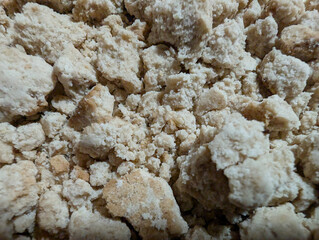 Macro view of crumbled and broken traditional Spanish Christmas almond polvorón dessert texture with sesame seeds. Detailed crumbly texture and scattered sesame seeds, appetizing classic treat sample.
