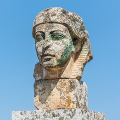 Obraz premium Ancient stone head sculpture against a clear blue sky